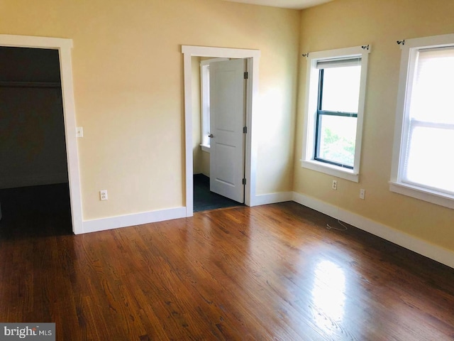 unfurnished bedroom with dark wood-type flooring and a walk in closet