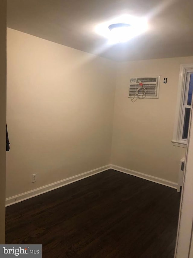 empty room with a wall mounted AC and dark hardwood / wood-style floors