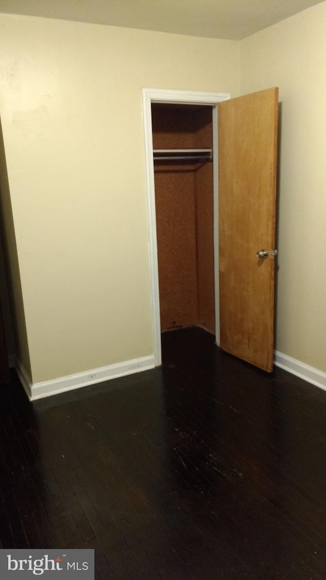 unfurnished bedroom featuring a closet and dark wood-type flooring