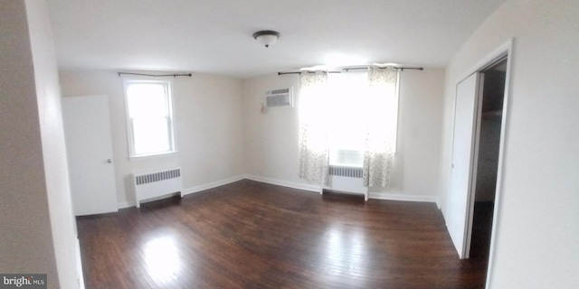 empty room with radiator heating unit, a wealth of natural light, and dark wood-type flooring