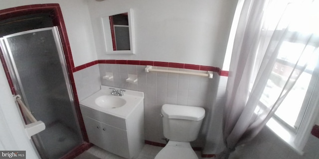 bathroom featuring an enclosed shower, toilet, vanity, and tile walls