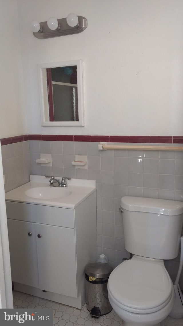 bathroom with vanity, toilet, tile walls, and tile patterned floors