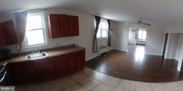 kitchen featuring sink, radiator heating unit, plenty of natural light, and light tile patterned flooring