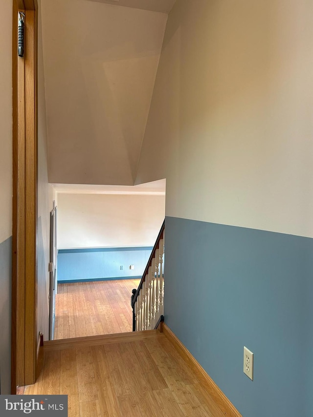 stairs featuring wood-type flooring and vaulted ceiling