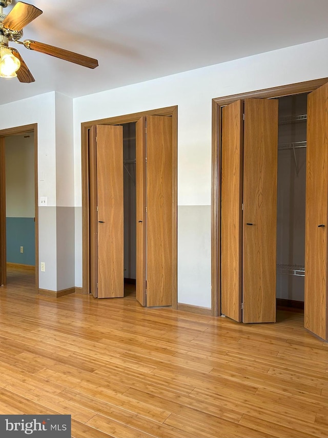 unfurnished bedroom featuring multiple closets, ceiling fan, and light hardwood / wood-style flooring