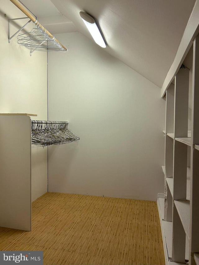 walk in closet featuring vaulted ceiling and light wood-type flooring