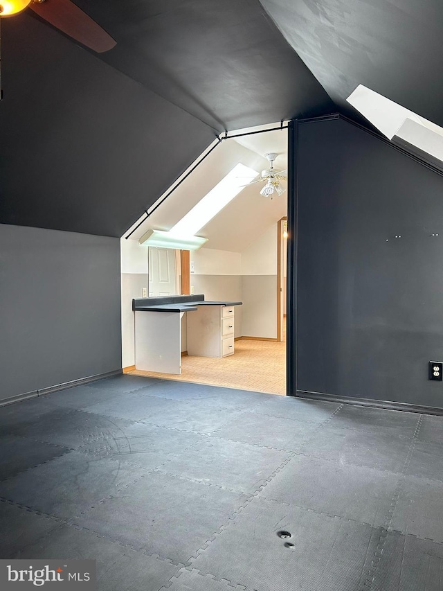 additional living space with ceiling fan and lofted ceiling with skylight