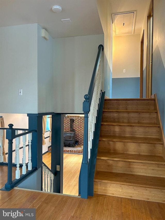 stairway with hardwood / wood-style floors and a wood stove