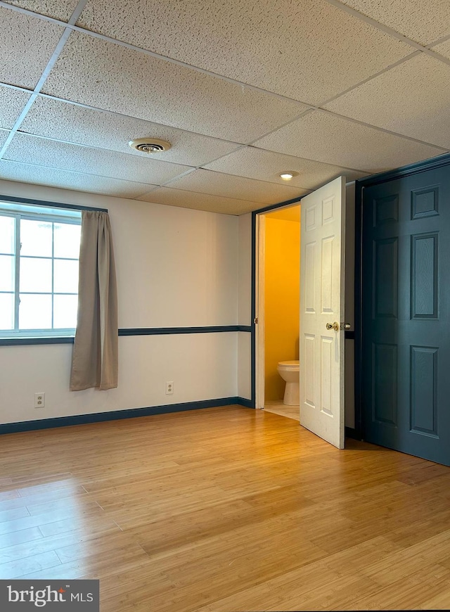 unfurnished room featuring hardwood / wood-style flooring and a paneled ceiling