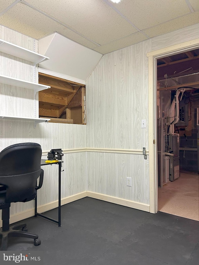 home office featuring wooden walls and a drop ceiling