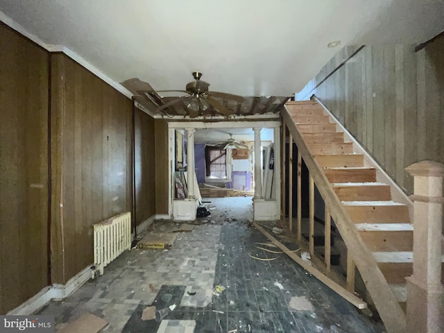 interior space with ceiling fan, radiator heating unit, and wood walls