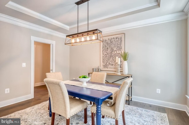 dining area with a raised ceiling, crown molding, and dark hardwood / wood-style flooring