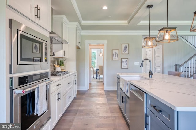 kitchen with sink, appliances with stainless steel finishes, an island with sink, white cabinets, and decorative light fixtures