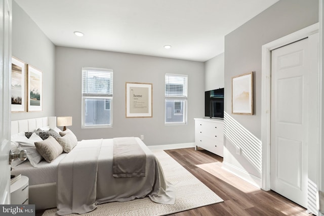 bedroom with hardwood / wood-style flooring and multiple windows