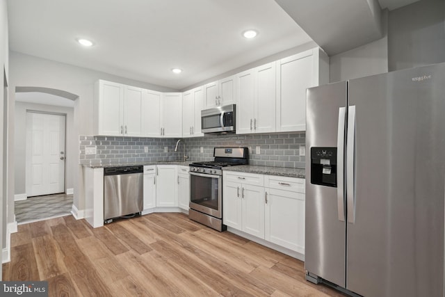 kitchen featuring light stone counters, white cabinets, light wood-type flooring, and appliances with stainless steel finishes