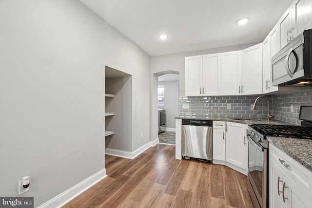 kitchen with sink, white cabinets, dark stone counters, and appliances with stainless steel finishes