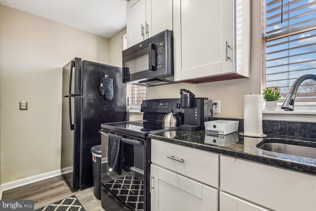 kitchen featuring black appliances, white cabinetry, a healthy amount of sunlight, and dark stone countertops