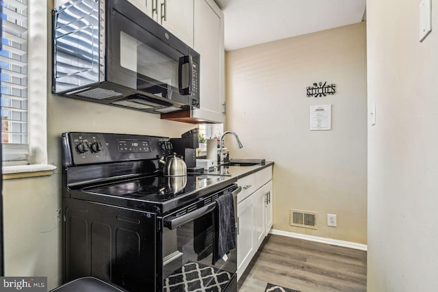 kitchen with hardwood / wood-style flooring, sink, white cabinets, and black appliances