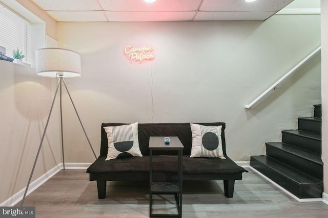 sitting room featuring wood-type flooring and a drop ceiling