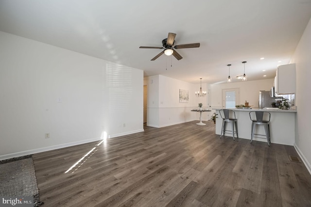 unfurnished living room with ceiling fan with notable chandelier and dark hardwood / wood-style floors