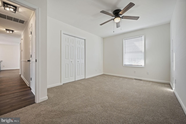 unfurnished bedroom featuring dark carpet, ceiling fan, and a closet