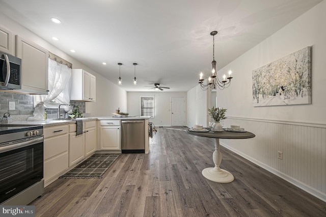 kitchen featuring stainless steel appliances, ceiling fan with notable chandelier, hanging light fixtures, and hardwood / wood-style floors