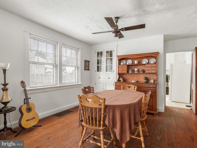 dining area with ceiling fan, dark hardwood / wood-style floors, and a textured ceiling