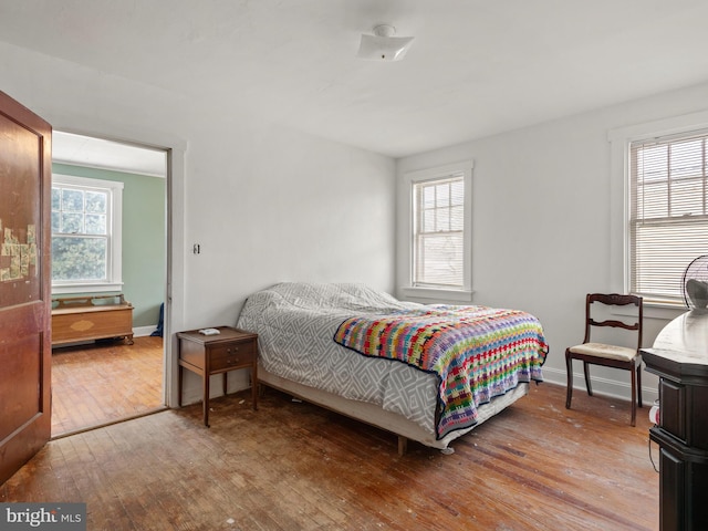 bedroom with multiple windows and hardwood / wood-style flooring