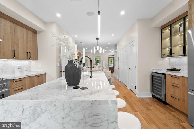 kitchen featuring wine cooler, a large island, decorative light fixtures, light hardwood / wood-style floors, and decorative backsplash