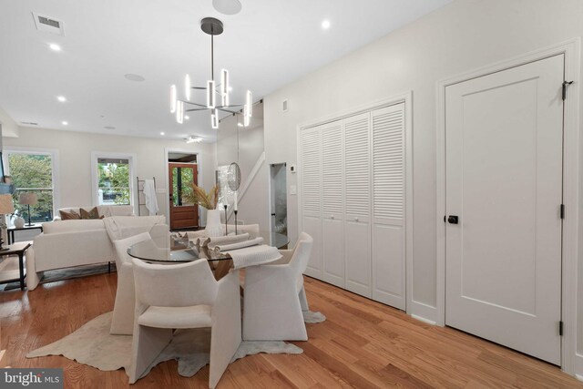 dining area featuring light wood-type flooring and a notable chandelier