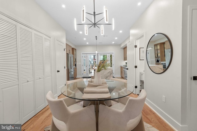 dining room with light wood-type flooring and a notable chandelier