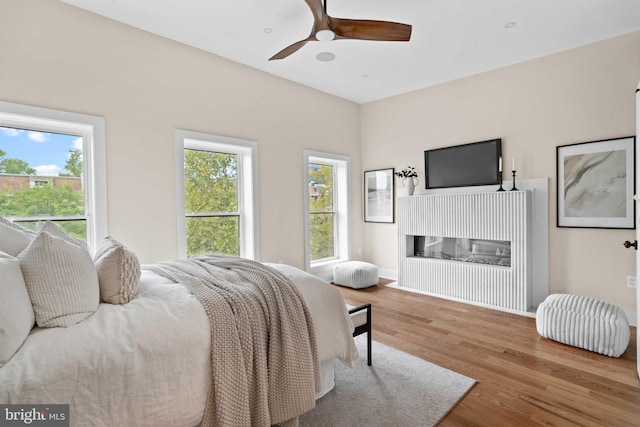 bedroom featuring light hardwood / wood-style floors, multiple windows, and ceiling fan