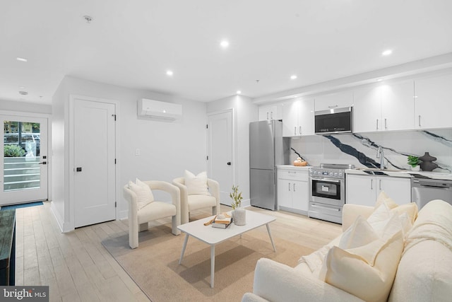 living room with sink, light hardwood / wood-style flooring, and a wall unit AC