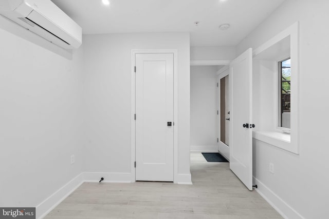 interior space with light wood-type flooring and a wall mounted air conditioner