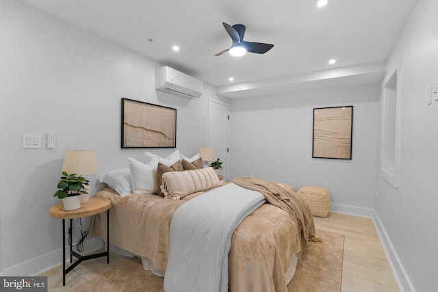 bedroom featuring light wood-type flooring, a wall mounted air conditioner, and ceiling fan