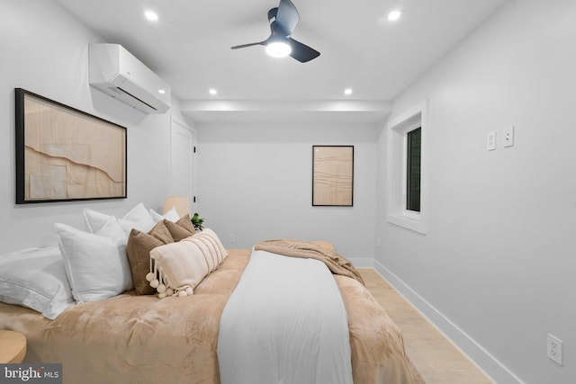 bedroom featuring light wood-type flooring, a wall mounted air conditioner, and ceiling fan