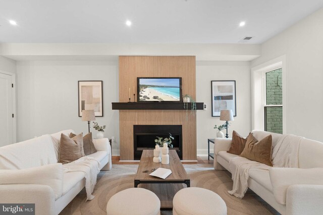 living room featuring a large fireplace and light hardwood / wood-style flooring