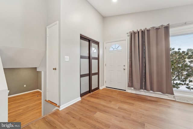 foyer featuring light wood-type flooring and vaulted ceiling