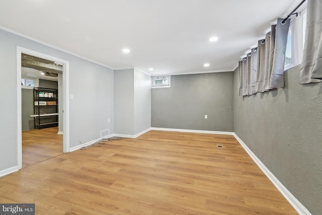 basement featuring crown molding and light hardwood / wood-style floors