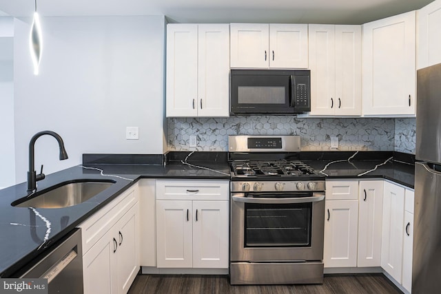 kitchen with sink, appliances with stainless steel finishes, dark stone countertops, hanging light fixtures, and white cabinets