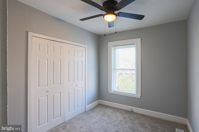 unfurnished bedroom featuring light colored carpet, a closet, and ceiling fan