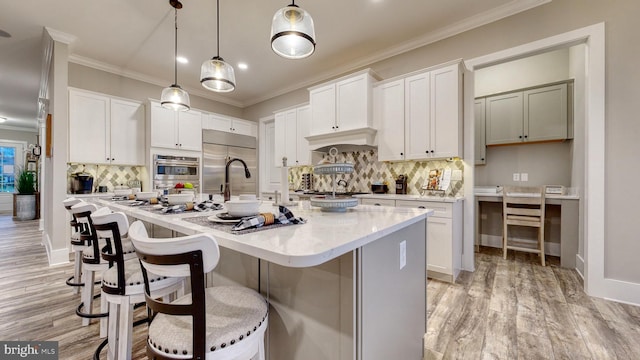 kitchen with a kitchen island with sink, white cabinetry, and stainless steel appliances