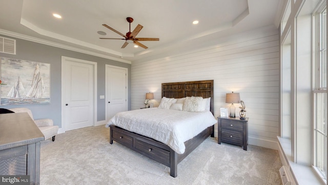 bedroom featuring crown molding, ceiling fan, light colored carpet, a tray ceiling, and wood walls