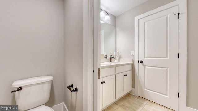 bathroom with toilet, vanity, and tile patterned flooring