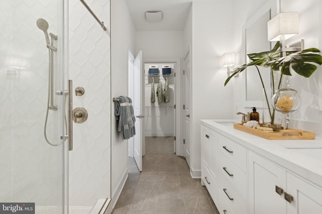 bathroom with a shower with shower door, vanity, and tile patterned flooring