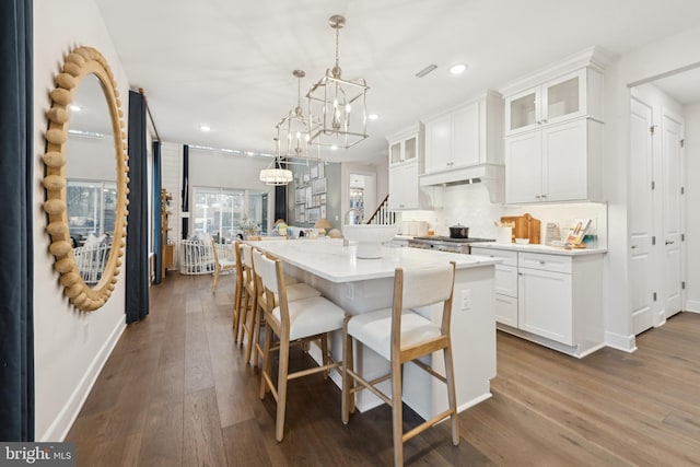 kitchen with white cabinetry, stove, a kitchen island, pendant lighting, and dark hardwood / wood-style floors