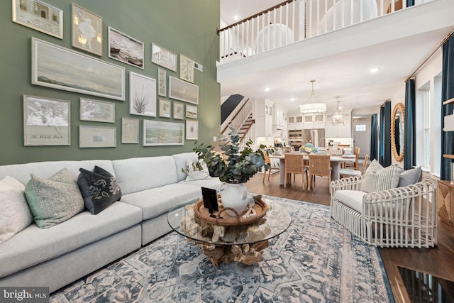 living room featuring wood-type flooring, a towering ceiling, and an inviting chandelier