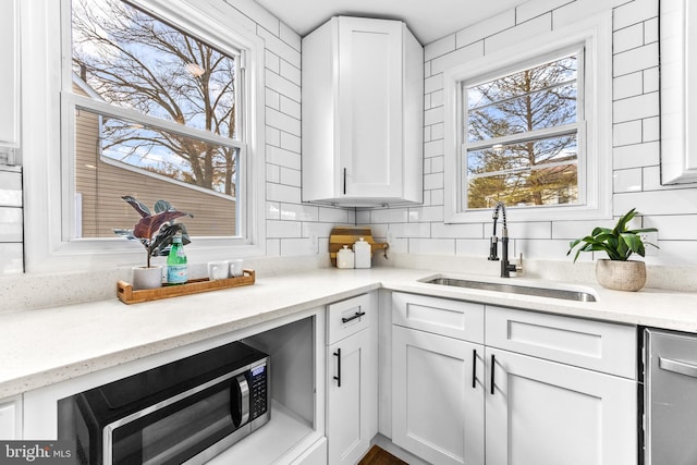 kitchen with white cabinetry, light stone countertops, and sink