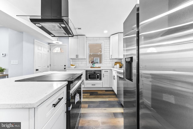 kitchen featuring stainless steel appliances, white cabinetry, island range hood, and backsplash