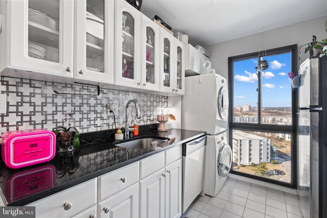 kitchen featuring stainless steel appliances, white cabinetry, stacked washer / drying machine, and sink